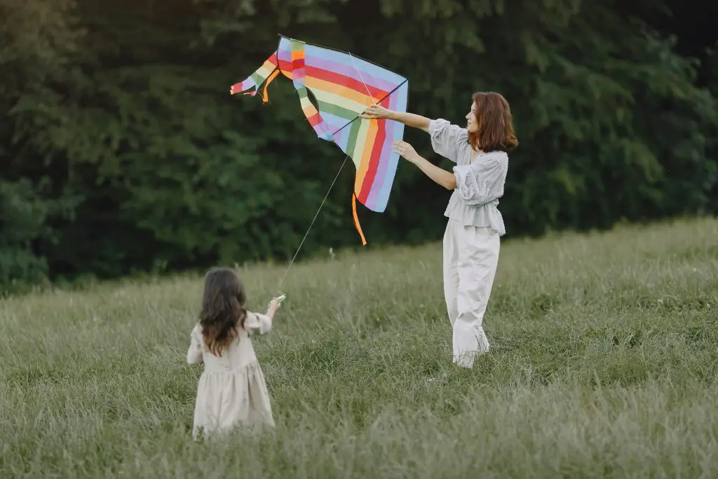 mother and daughter flying a kite in a field