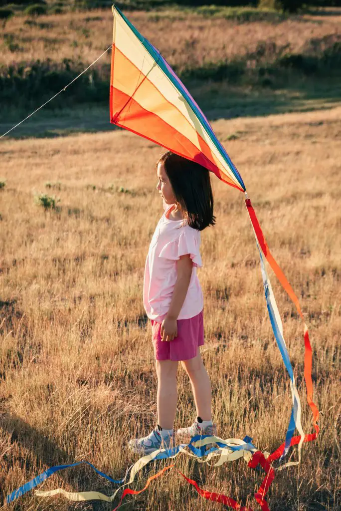 young girl holding kite in grass field